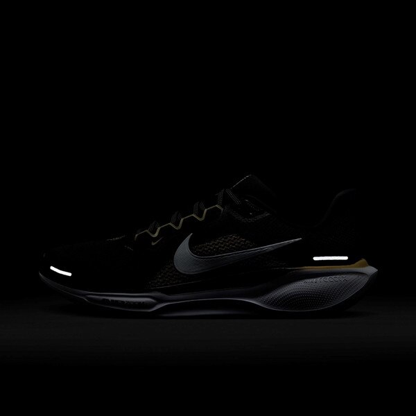 Side view of black Nike running shoe in the dark, showing reflective Swoosh, heel strip, and toe detail on white sole